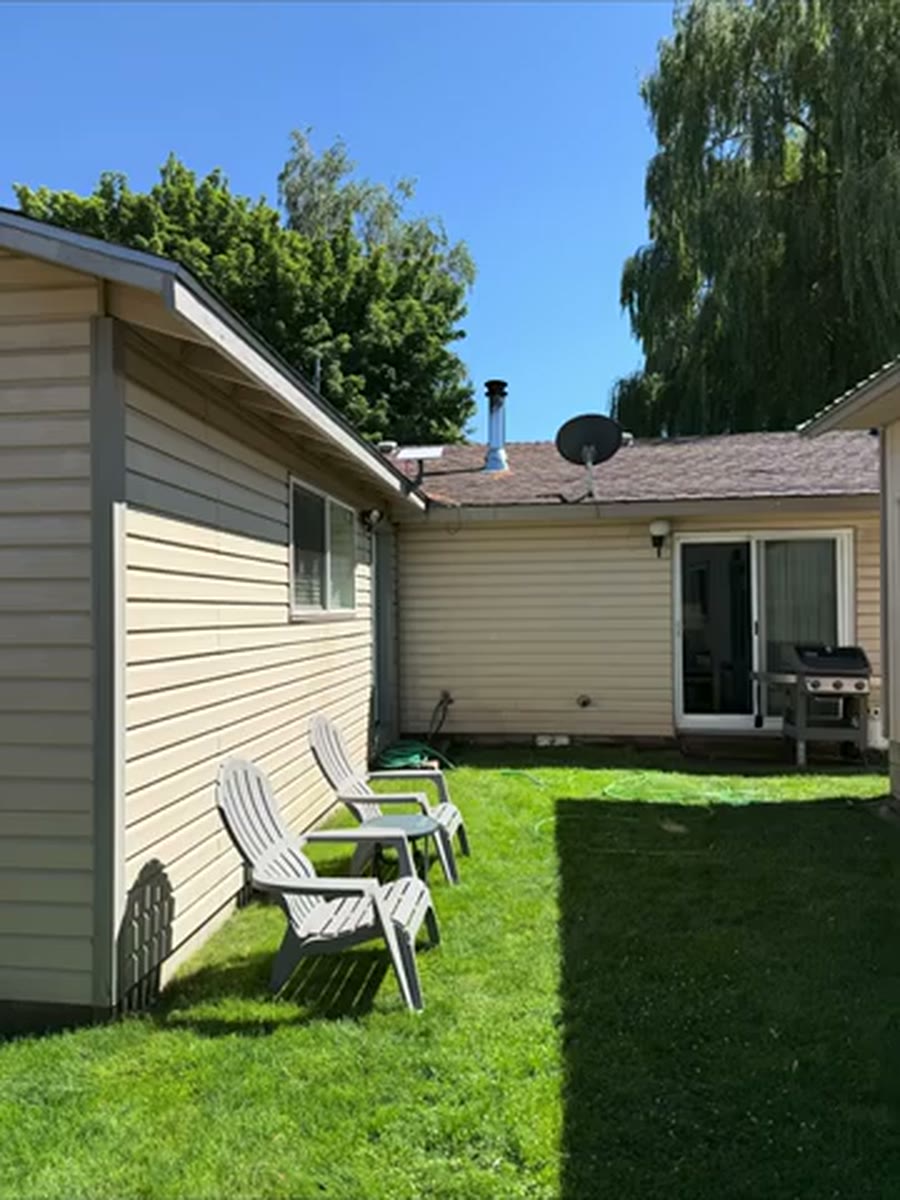 Clean beige residential siding around a sunny backyard after soft washing