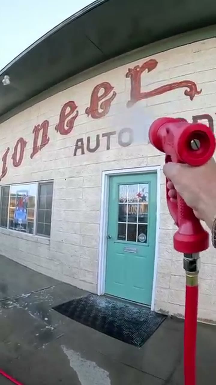 Soft washing the painted masonry storefront at Pioneer Auto Body
